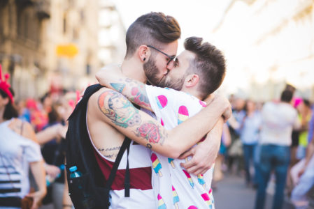 Two gay men at Gay Pride Parade kissing and celebrating LGBT strengths