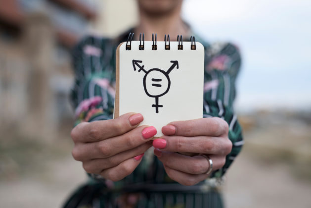 Woman fighting internalized transphobia with multiple gender symbols
